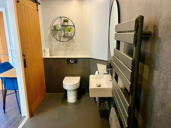 Une petite salle de bain comprenant des toilettes, un lavabo et une étagère fixée au mur, agrémentée de plantes.