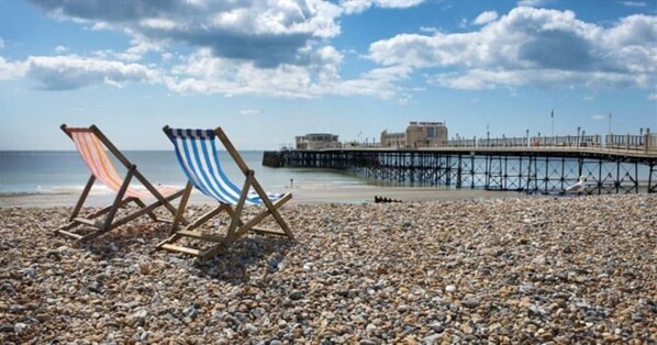 A pebbled beach with two striped beach chairs and a pier in the background. - Luxury lodge with hot tub at foot of South Downs, near beach Ferring West Sussex (Ferring)