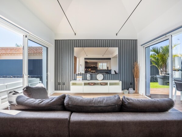 A modern living room with a grey sofa, a white console table, and a large mirror. - Villa Diana- Jacuzzi, Heated Pool & BBQ (El Madroñal)