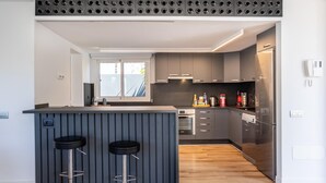 A modern kitchen with a central island, two bar stools, and a built-in oven.