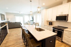 A modern kitchen with a central island, stainless steel appliances, and white cabinetry.