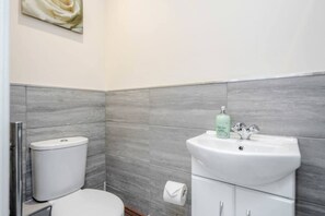Une salle de bain équipée de toilettes, d’un lavabo et d’un porte-rouleau de papier toilette.