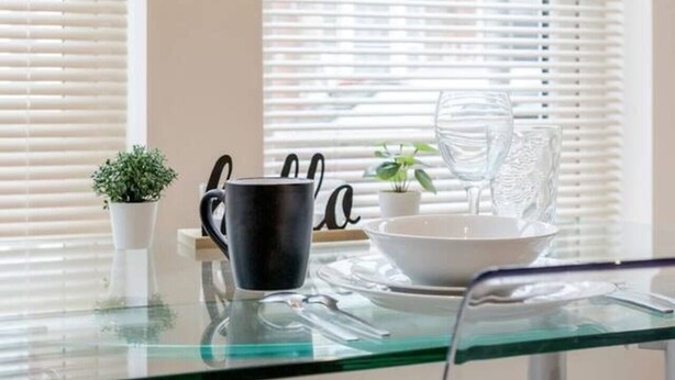 A modern kitchen with a glass table, a black mug, a white bowl, and a small potted plant. - Homely Spaces Apt A, Large Studio W/king, 2guests (Bedford)