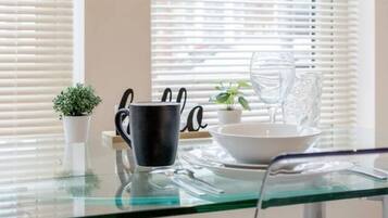 A modern kitchen with a glass table, a black mug, a white bowl, and a small potted plant.