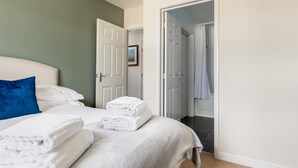 Una habitación de hotel con una cama bien tendida, una puerta que da al baño y un cuadro en la pared.