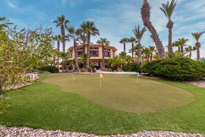 A golf course with a well-maintained lawn, several flags, and palm trees.