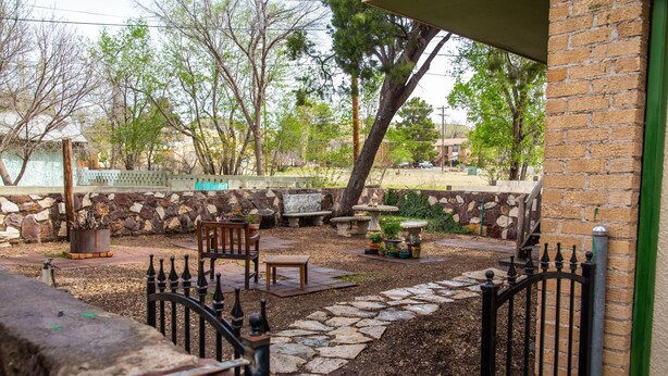 A patio area with stone walls, a wooden bench, a table, and a metal gate. - Langridge Lodge Studio Residence by RedAwning (Alpine)