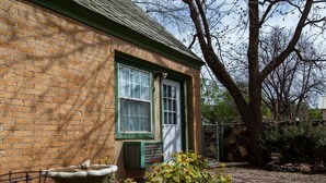 A brick building with a green door and windows, a bird bath, and a tree in the background. - Langridge Lodge Studio Residence by RedAwning (Alpine)