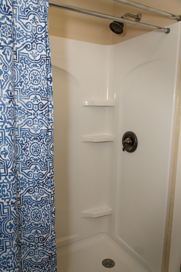 A shower stall with a patterned curtain, a showerhead, and a door with a handle. - Langridge Lodge Studio Residence by RedAwning (Alpine)