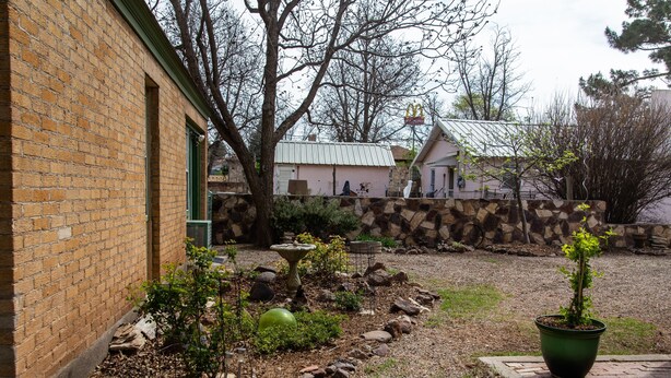 A brick building with a stone wall, a garden with a potted plant, and a small pond. - Langridge Lodge Studio Residence by RedAwning (Alpine)