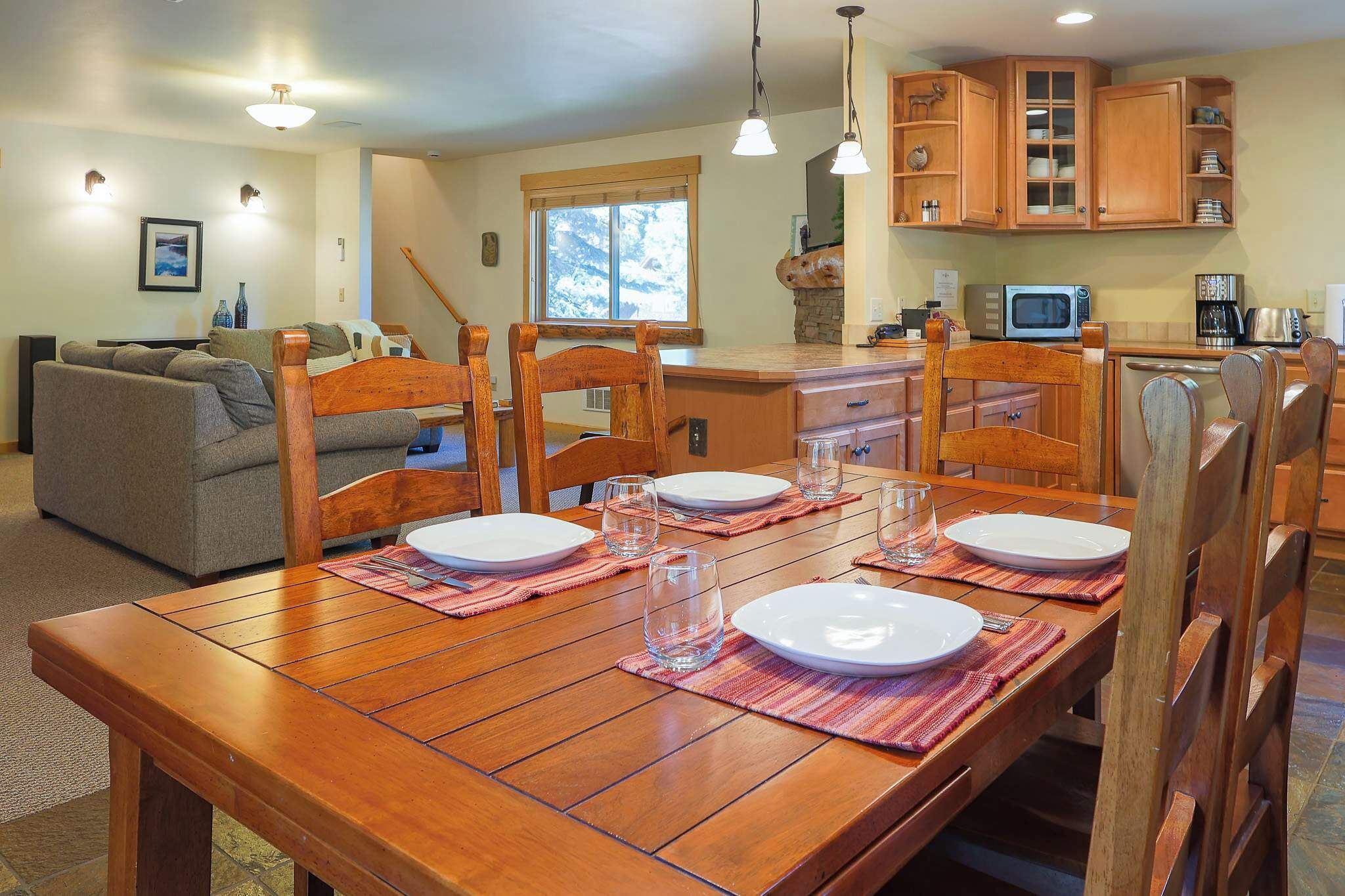 Un comedor con una mesa de madera dispuesta para cuatro personas, rodeada de sillas de madera.