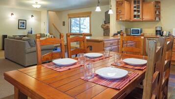 Un comedor con una mesa de madera dispuesta para cuatro personas, rodeada de sillas de madera.