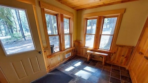 A wooden cabin interior with large windows, a bench, and a door. - Elk Lodge: Spacious Cabin Near Trails & Ski Access (Winthrop)