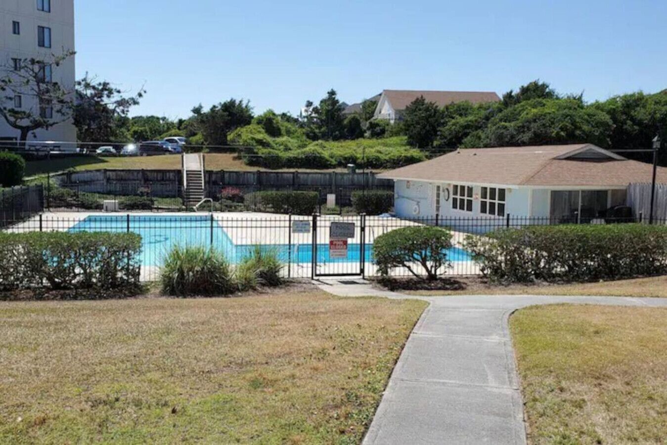 A residential area with a swimming pool, fenced yard, and a building with a sloped roof.