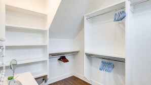 Un closet amplio con repisas abiertas, un espejo y percheros para ropa.