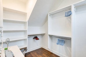 Een inloopkast met open planken, een spiegel en kledingroedes.