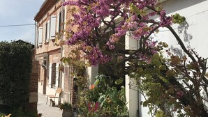 A building with a brick facade, a balcony, and a tree with purple flowers. - Gîte & Bed and Breakfast capacity 14 people with swimming pool, labeled 4 keys. (MAUVAISIN)