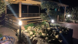 A wooden deck with a railing, surrounded by rocks and plants, under a night sky. - Gîte & Bed and Breakfast capacity 14 people with swimming pool, labeled 4 keys. (MAUVAISIN)