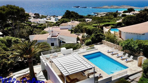 Ein Poolbereich mit Liegestühlen und Blick aufs Meer.
