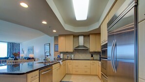 Una cucina moderna con mobili chiari in legno, elettrodomestici in acciaio inossidabile e un'isola centrale.