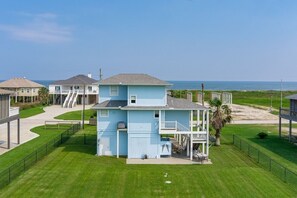 A two-story house with a balcony, a covered patio, and a view of the ocean. - Bolivar Del Mar 3 Bedroom Home by RedAwning (Port Bolivar)