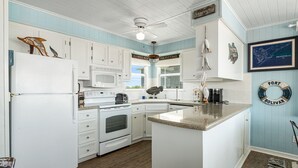 Una cucina con mobili bianchi, un'isola centrale, un forno a microonde e una macchina per il caffè.