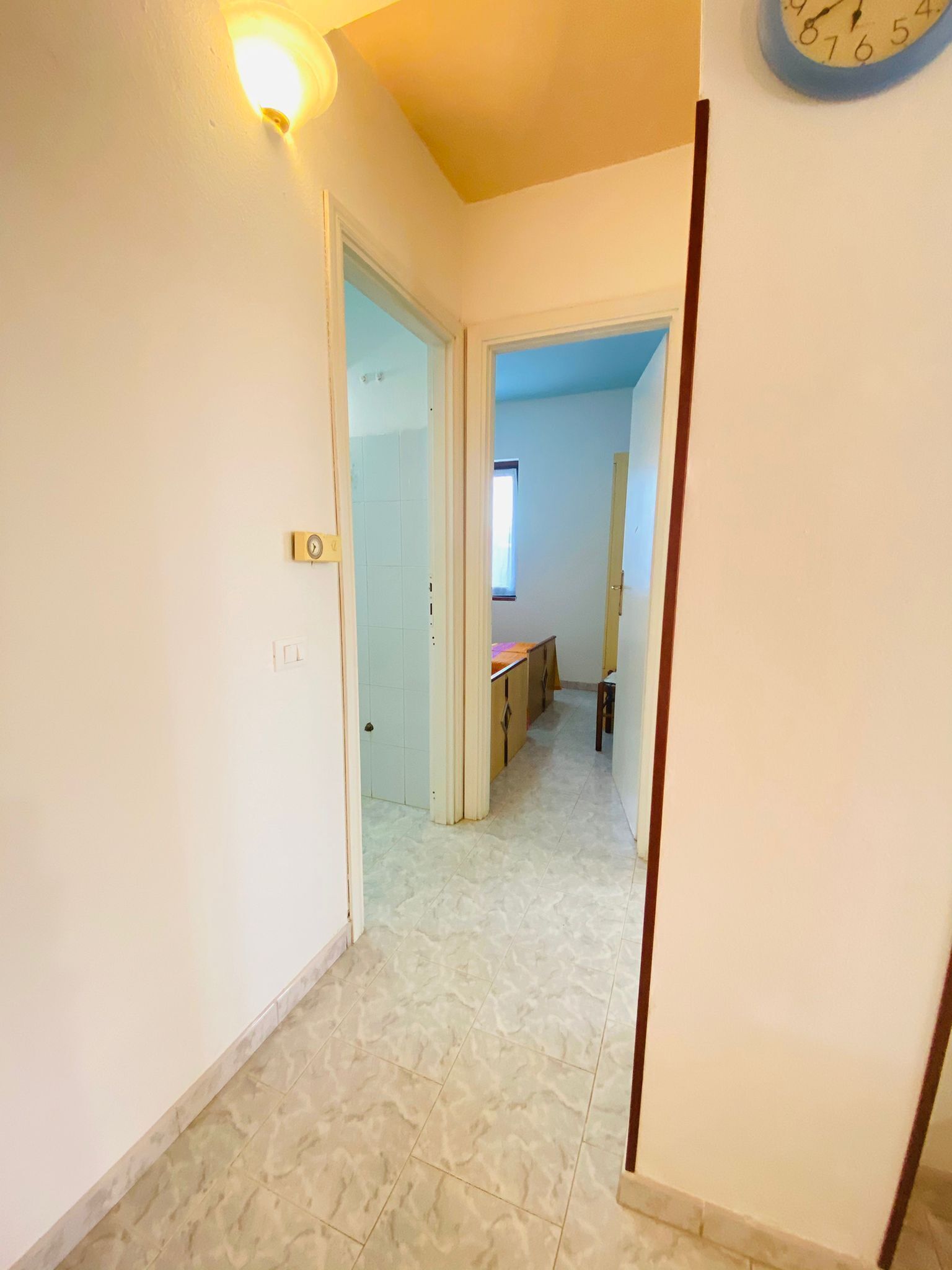 Un pasillo con piso de baldosas que conduce a una habitación con ventana y puerta.