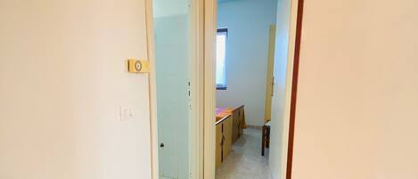 Un pasillo con piso de baldosas que conduce a una habitación con ventana y puerta.