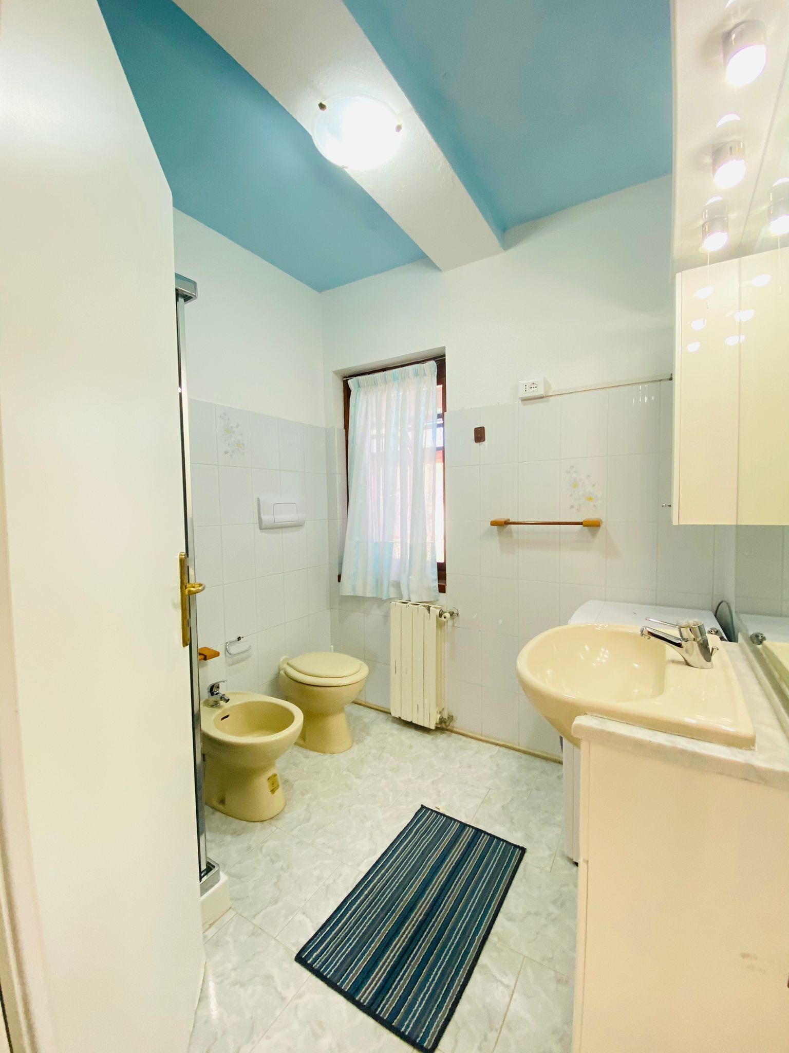 A bathroom with a toilet, bidet, sink, and a mirror.
