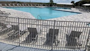 A pool area with multiple lounge chairs and a fenced deck. - Ocean Villa C203 - Balcony Views (Hilton Head Island)
