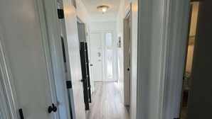 A hallway with white doors and light wood flooring. - Ocean Villa C203 - Balcony Views (Hilton Head Island)
