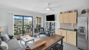 Uma sala de estar moderna com um sofá, uma mesa de madeira e uma varanda com móveis para área externa.