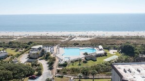 Vista aèria d'un complex turístic amb una piscina gran, platja i una carretera que hi condueix.