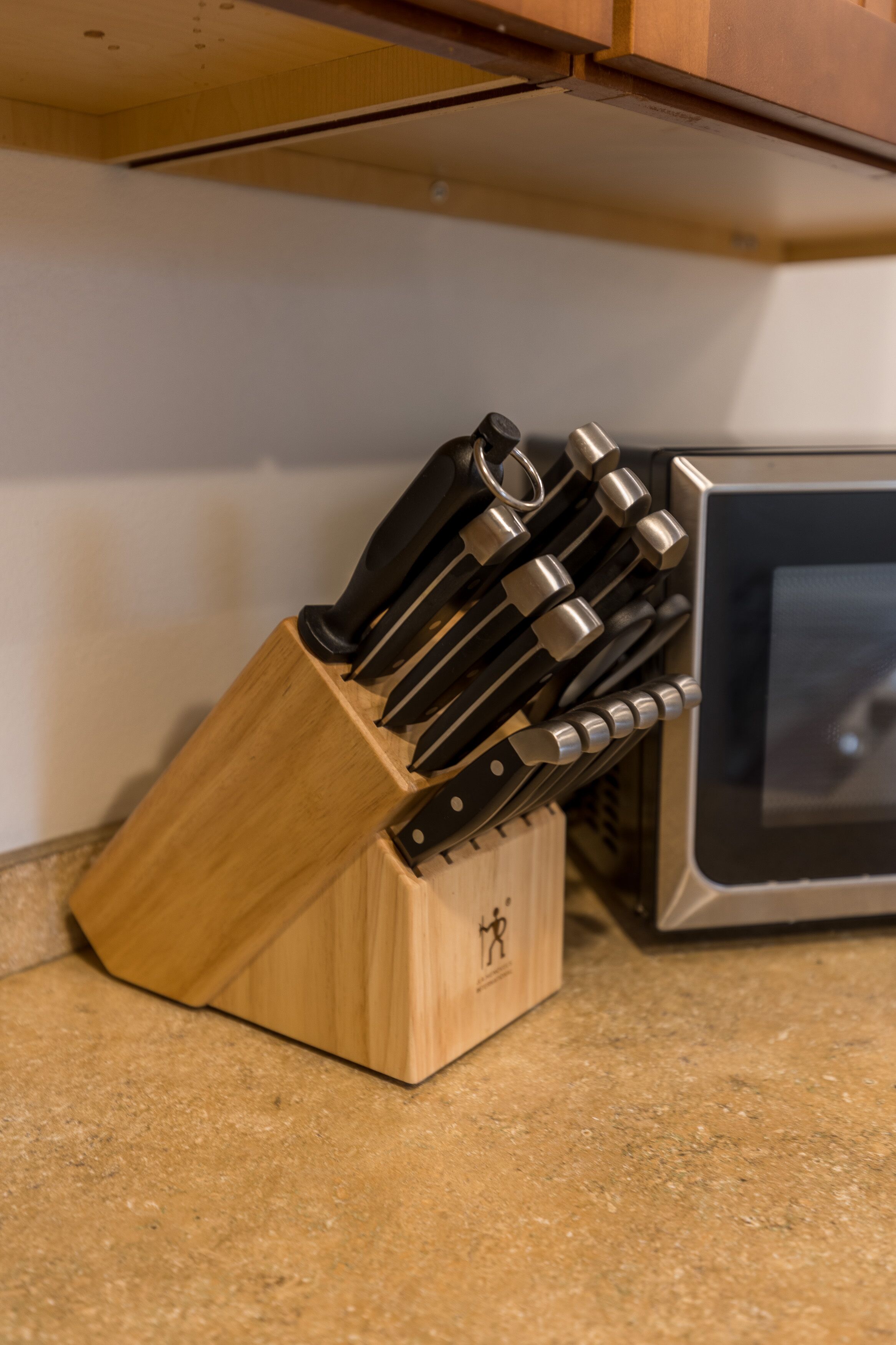 Un bloque de madera con varios cuchillos sobre una encimera de cocina.