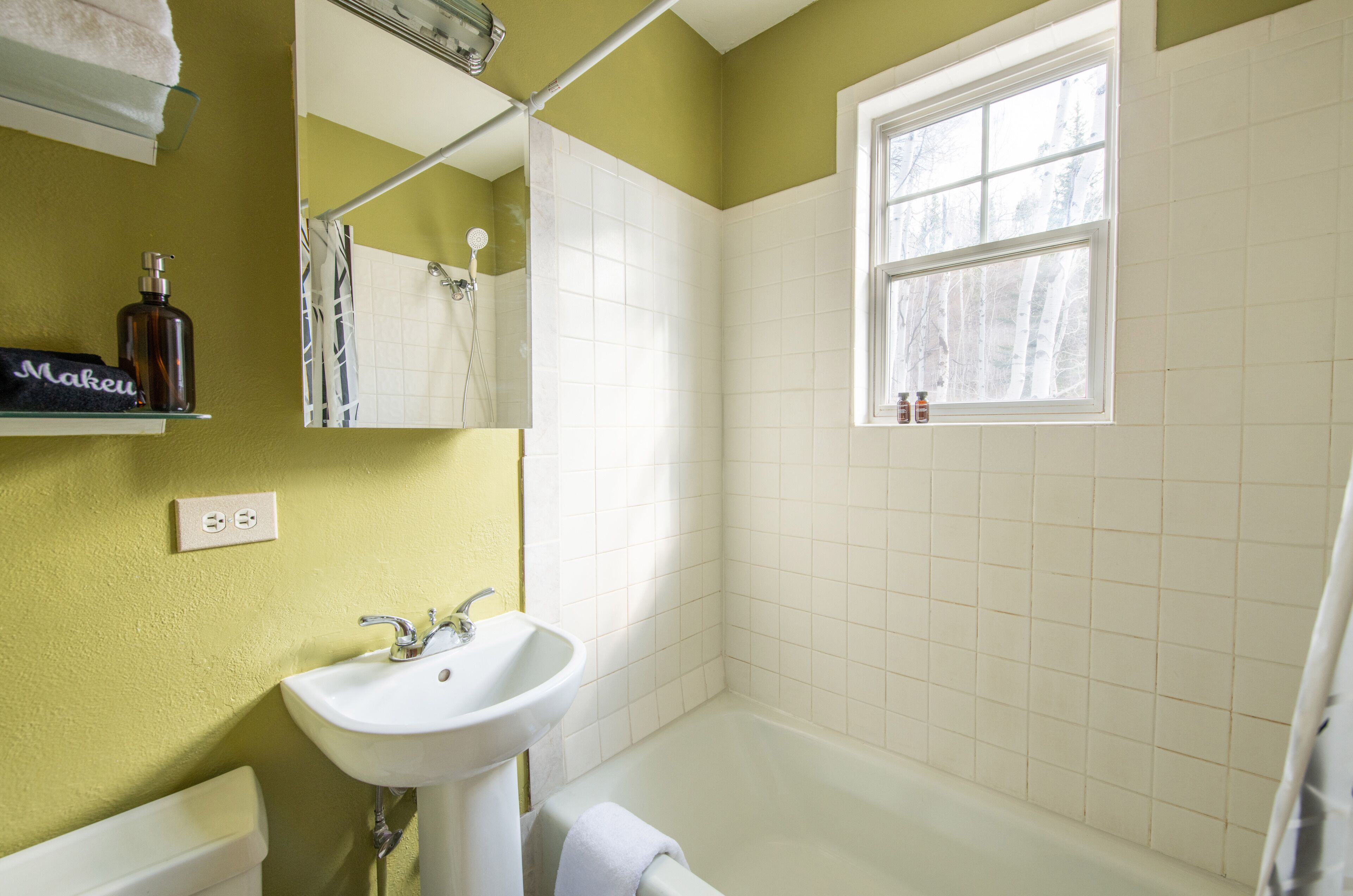 A bathroom with a white sink, a mirror, and a window.