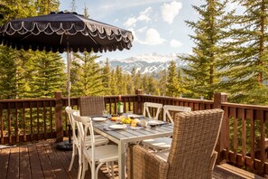 Eine Terrasse mit Esstisch, mit Blick auf eine gebirgige Landschaft.