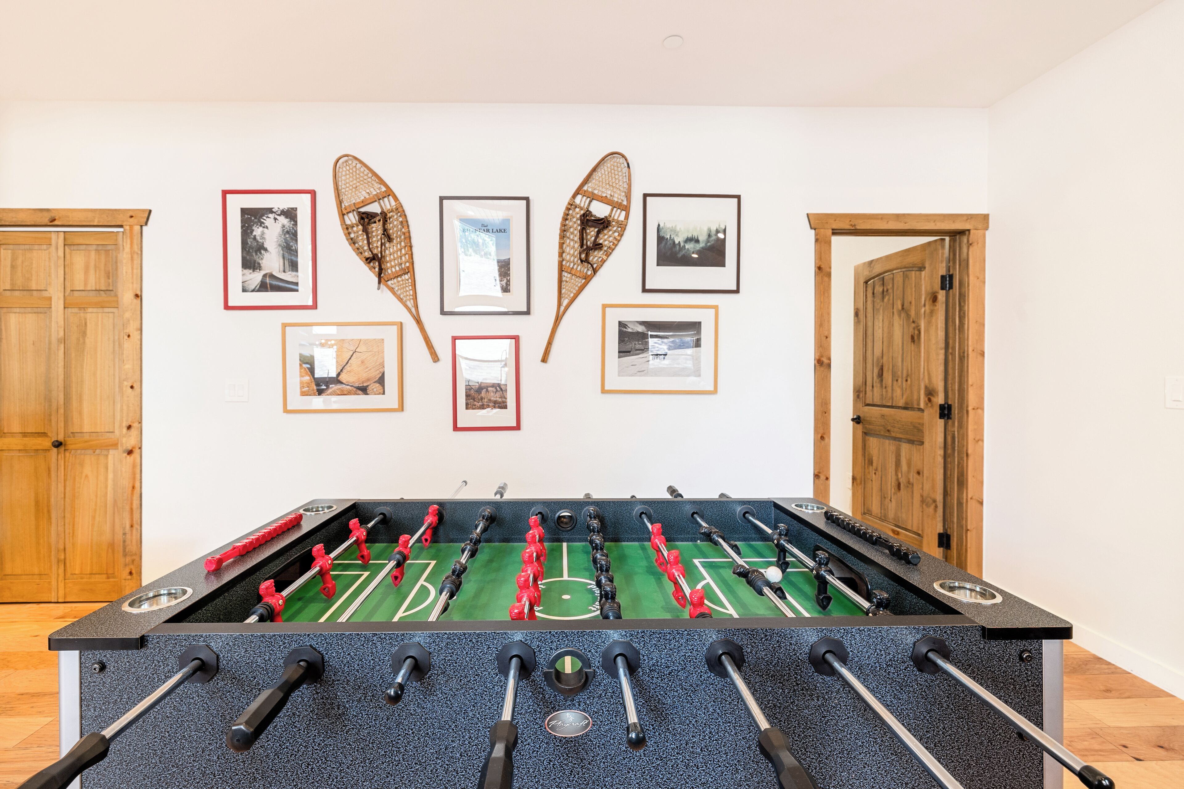 Una mesa de fútbol de mesa en una habitación con puertas de madera y cuadros en la pared.