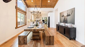 Una cocina amplia con una mesa de comedor de madera, una araña y un cuadro grande de un ciervo en la pared.