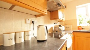 A kitchen with wooden cabinets, a kettle, and labeled containers for tea, sugar, and coffee. - Fantastic 2-bed House in Hull. Garden, Sky tv (Hull)