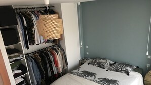 Un dormitorio con cama, armario y lámpara colgante.