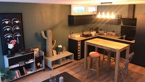 Una cocina moderna con una isla de madera, taburetes de bar, horno empotrado y un televisor de pantalla plana montado sobre la encimera.