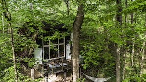 Eine Hütte mit einer Terrasse, umgeben von dichtem Wald.