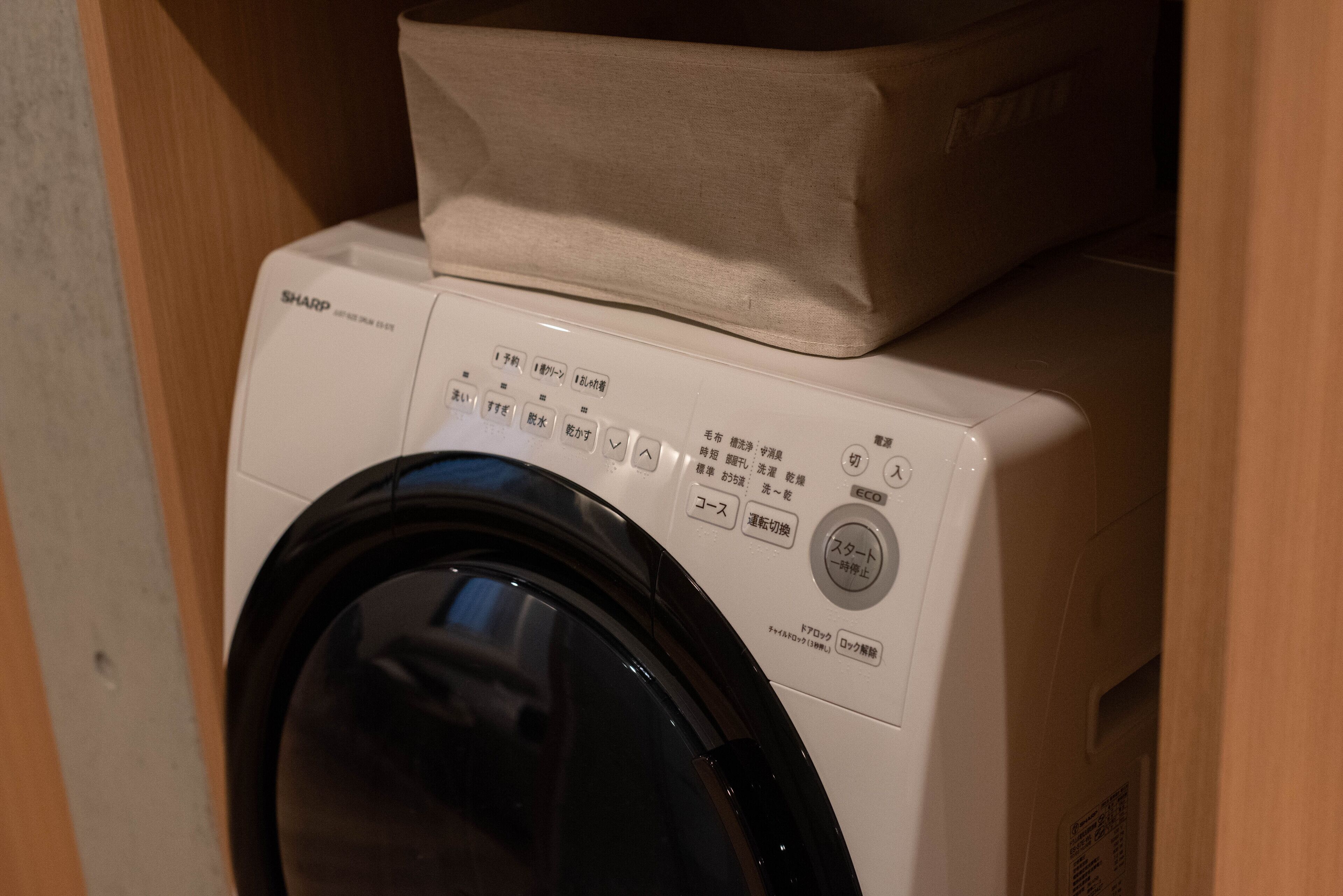 Vue de face d’un lave-linge, avec son panneau de commande et un panier à chargement par le dessus.