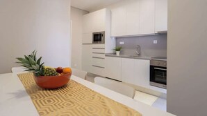 Eine moderne Küche mit weißen Schränken, einer Mikrowelle, einem Backofen und einem Essbereich mit Tisch und Stühlen.
