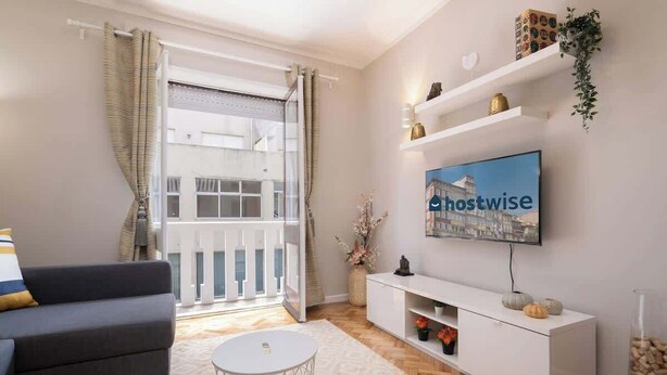 Ein modernes Wohnzimmer mit einem grauen Sofa, einem weißen Couchtisch und einem an der Wand montierten Fernseher, der 'hostwise' anzeigt.