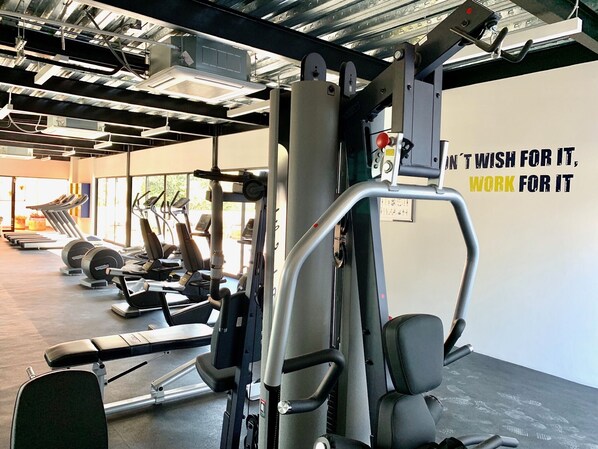 A gym with various exercise equipment, including treadmills and weight machines, and a motivational quote on the wall.