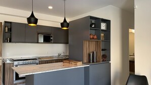 A modern kitchen with a central island, dark cabinetry, and pendant lighting. - Luxury & safety. PALCCO, Akron, ITESM, ValleReal (ZAPOPAN)