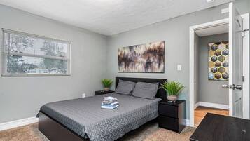 Relax in a serene bedroom with a large bed, two nightstands, and a unique piece of art.