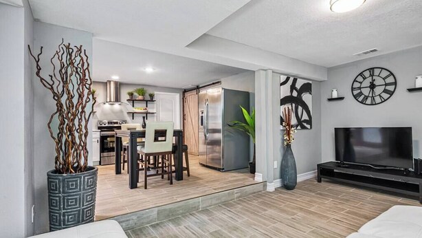 A modern living room with a sofa, a TV, and a dining area with chairs and a table.