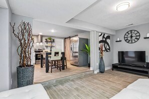 Een moderne woonkamer met een bank, een televisie en een eethoek met stoelen en een tafel.